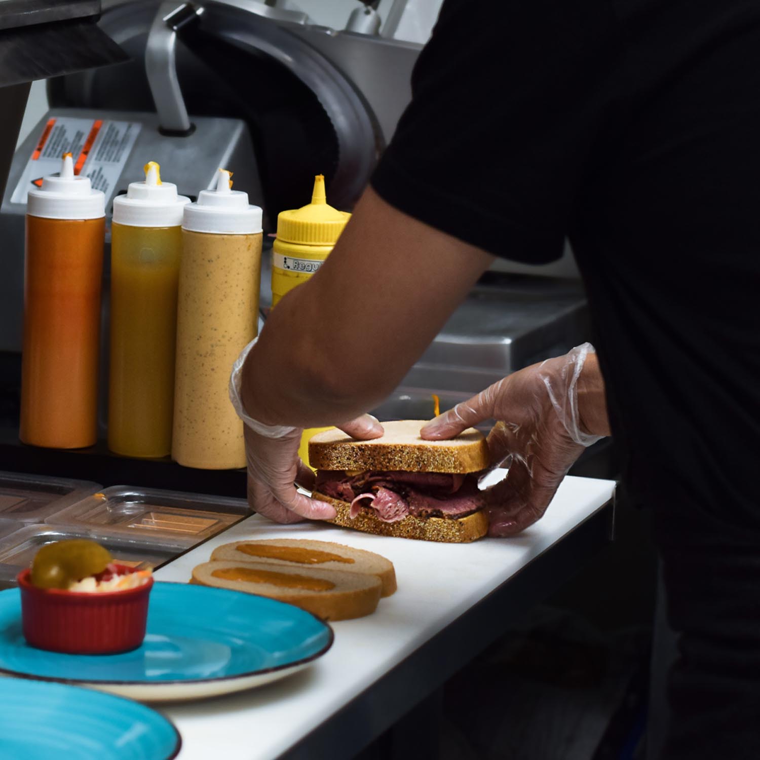 Restaurant kitchen employee working on preparing sandwich custom
